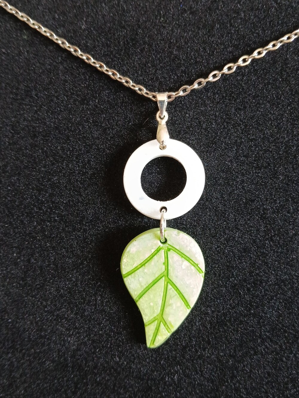 Shimmery green leaf and white circle pendant on silver stainless steel necklace